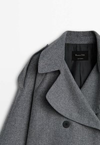 Manteau en laine gris croisé avec larges revers, épaulette, boutons noirs et doublure intérieure noire étiquetée Massimo Dutti.