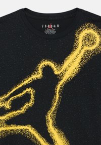 Mustast puuvillast T-särk, millel on suur kollane laiguline disain, mis meenutab logo. Klassikaline ümara kaelusega, sees väike brändi silt.