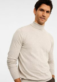 Helles beiges Rollkragensweatshirt mit geripptem Kragen und Bündchen, aus weichem Material gefertigt. Eng anliegendes Design mit langen Ärmeln und einer glatten Textur.