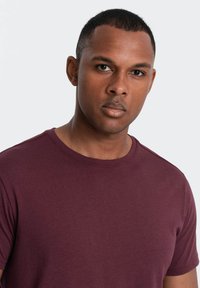 Bordeauxfarbendes T-Shirt mit Rundhalsausschnitt, kurzen Ärmeln, aus weichem Baumwollmaterial mit glatter Textur und minimalistischem Design.