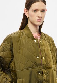 Khaki színű steppelt bomber dzseki bordázott gallérral, pattintós gombos záródással és oldalzsebekkel. Gyémántmintás és sima tapintású.