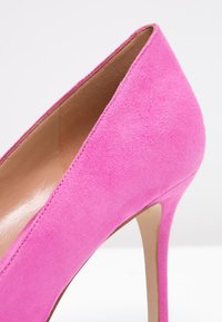 Růžová nubuková botka na vysokém podpatku s hladkým povrchem, špičatou špičkou a úzkým stiletto podpatkem. Čisté linie s minimálními akcenty.