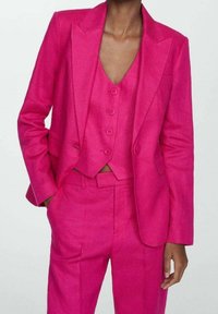 Costume ajusté fuchsia composé d'un blazer structuré avec des revers pointus, d'un gilet assorti avec boutons, et d'un pantalon tapered avec poches latérales.
