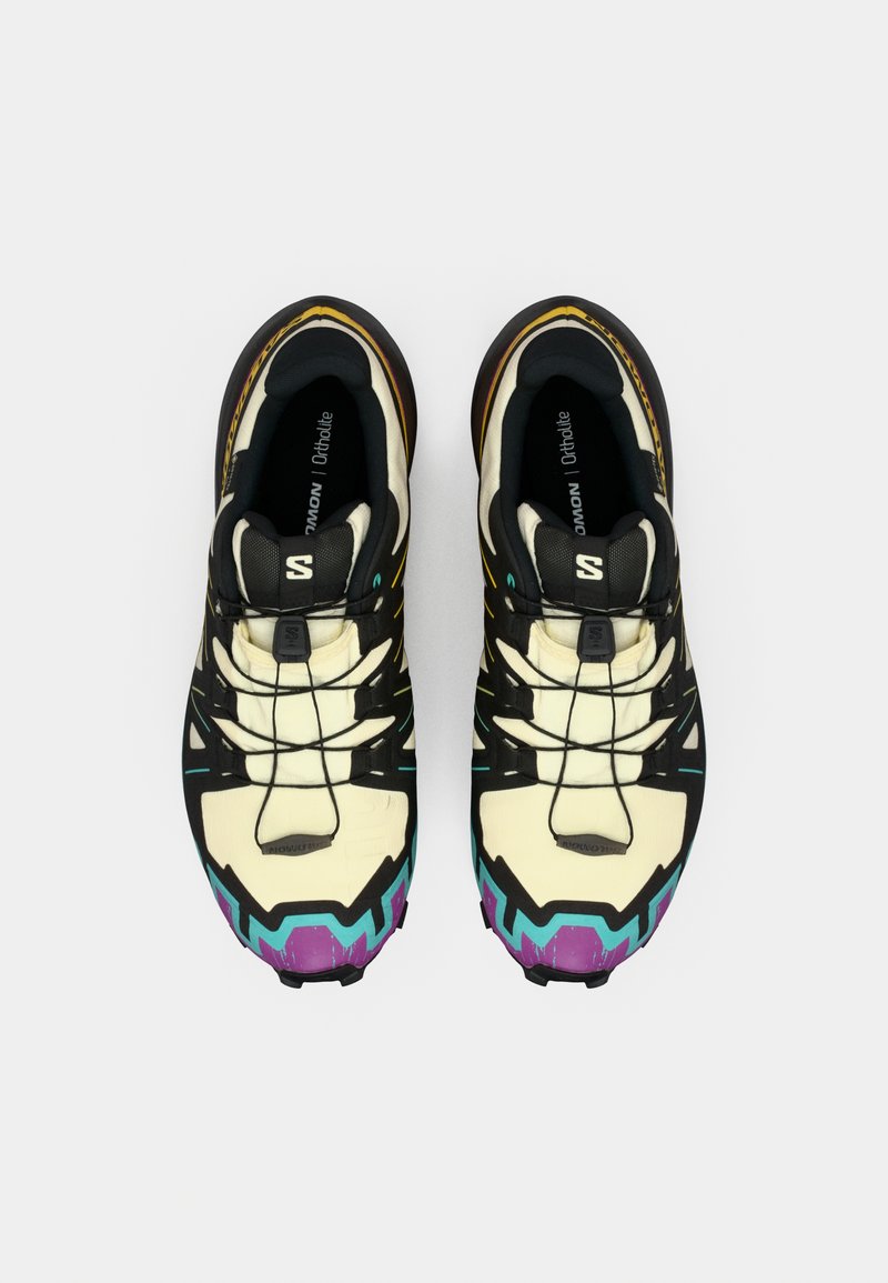 Multikleurige sportschoenen met een crèmekleurige bovenkant, zwarte accenten, paarse en turquoise details, en een gestructureerde zool voor grip.