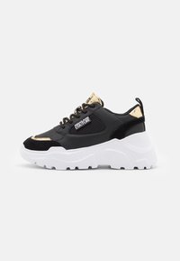 Svart sneaker med guldaccenter, mesh- och mockadetaljer. Kraftig vit sula, rund tå och snörning fram. Har logotyp på sidan.