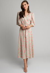 Kwiatowa sukienka w kolorze miętowym z różowymi akcentami, z rękawami o długości trzech czwartek, z wiązaniem w talii i spódnicą o średniej długości.