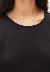 Zwarte top met een gladde, zachte textuur, voorzien van een ronde halslijn en een minimalistisch ontwerp. Geen zichtbare patronen of hardwaredetails.