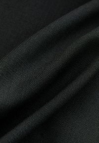 Black fabric with a textured surface, featuring a fine weave and slight sheen, showcasing folded layers for depth and dimension.