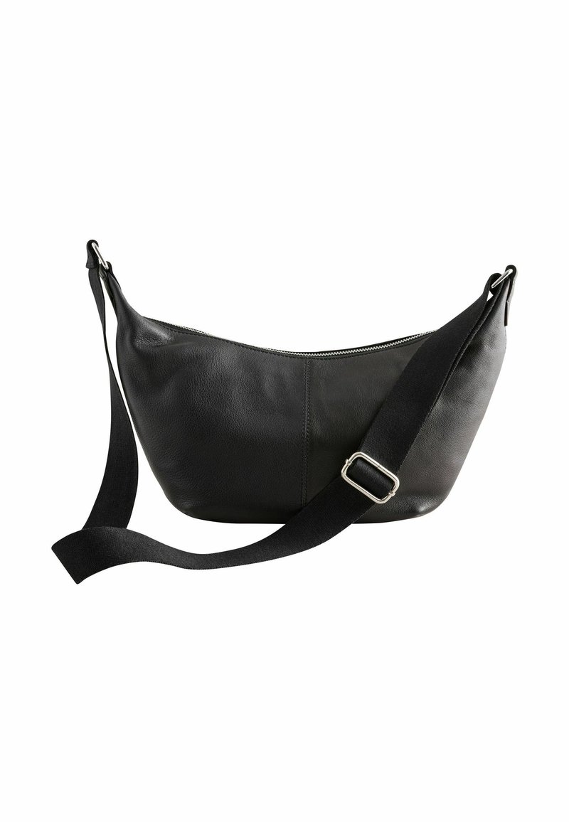 Sac bandoulière en cuir noir avec sangle en tissu noir réglable et boucle argentée, fermeture éclair sur le dessus, design simple et arrondi.