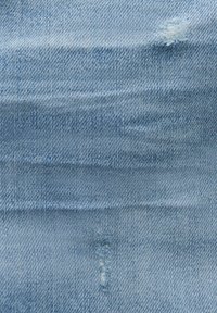 Lichtblauwe denimstof met een licht vervaagde textuur, met subtiele horizontale lijnen en een klein rafelig gaatje voor detail.