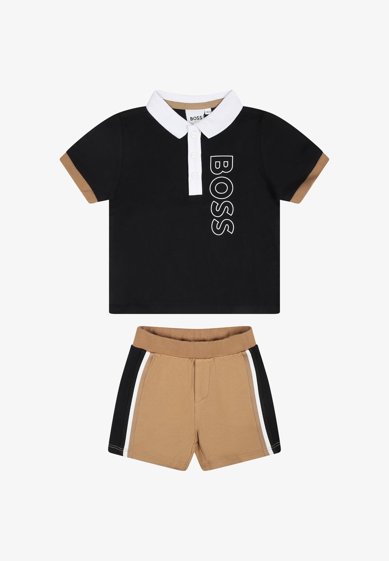 Polo noir avec un col blanc et le logo "BOSS", associé à un short beige avec des rayures latérales noires et blanches. Matière en coton.