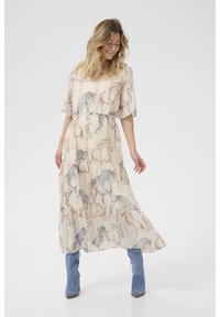 Hosszú ruha áttetsző, texturált anyagból, világos bézs háttérrel, kék és barna ló mintával, és megkötött derékkal.