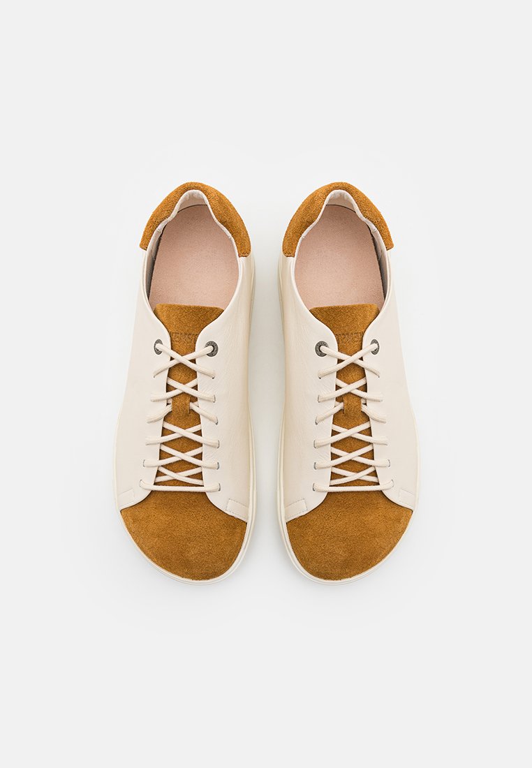 Helle beige Leder-Sneaker mit braunen Wildlederakzenten, flachen Schnürsenkeln und einem runden Zehendesign. Mit einer strukturierten Sohle für besseren Halt.