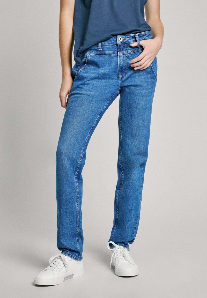 Blå jeans i denim med rak benpassform, fem-ficksdesign och subtila blekningar. Matchas med vita sneakers och en mörk skjorta.