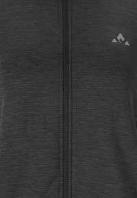 Svart atletisk zip-up jacka med en texturerad yta, försedd med en svart dragkedja och en liten grå logotyp på övre vänstra sidan.