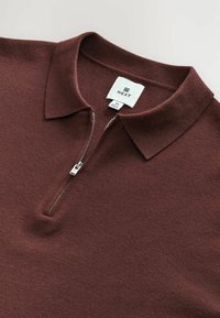 Bordo polo marškiniai, pagaminti iš švelnaus audinio, su apykakle ir pusiau užtrauktuku. Etiketėje parašyta "NEXT", dydis M, su lygiu tekstūru ir minimalistiniu dizainu.