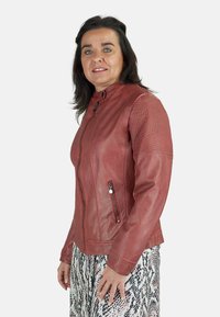 Chaqueta de cuero rojo con un diseño entallado, que cuenta con un cierre frontal y acentos de rayas verticales en los hombros. Textura suave, sin patrones.