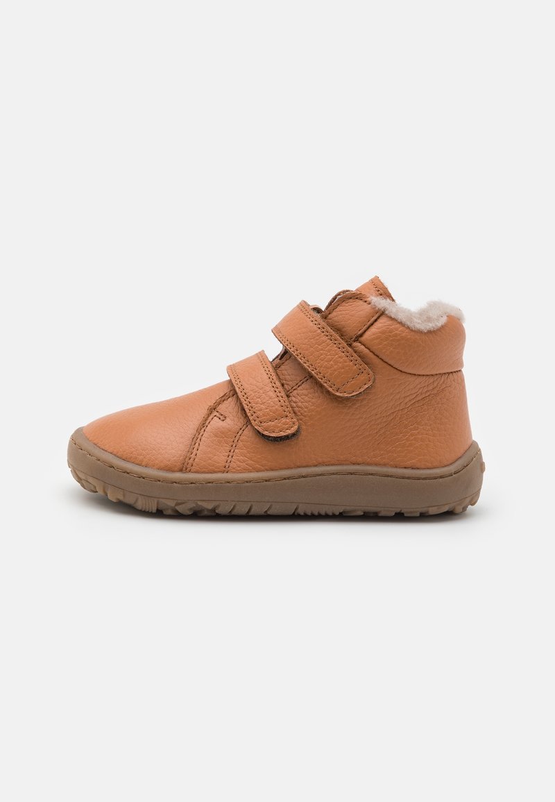 Chaussure pour tout-petit en cuir marron avec deux bandes Velcro, col matelassé, doublure en laine et semelle en caoutchouc texturée, présentée de profil sur fond blanc.