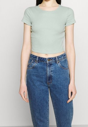 Mint green cropped t-shirt in a ribbed texture, paired with high-waisted blue denim jeans featuring five pockets and a button closure.