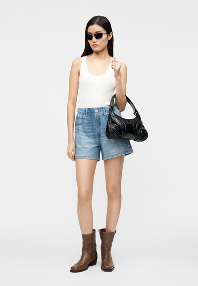 Débardeur blanc à côtes, short en denim bleu clair, bottes de cowboy marron, et sac à bandoulière noir avec un design texturé et des poignées arrondies.