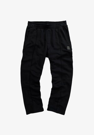 Černé tepláky vyrobené z měkké tkaniny, s elastickým pasem, bočními kapsami a malou nášivkou loga na přední straně.