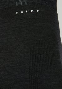 Leggings negros sin costuras con secciones texturizadas y el logo impreso "FALKE" cerca de la cintura. Tejido suave y elástico para mayor comodidad.