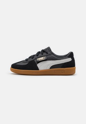 Baskets Puma en cuir et daim noir, avec des accents gris, lacets ronds et semelle extérieure en caoutchouc gomme. Logo PUMA sur le côté et la languette.