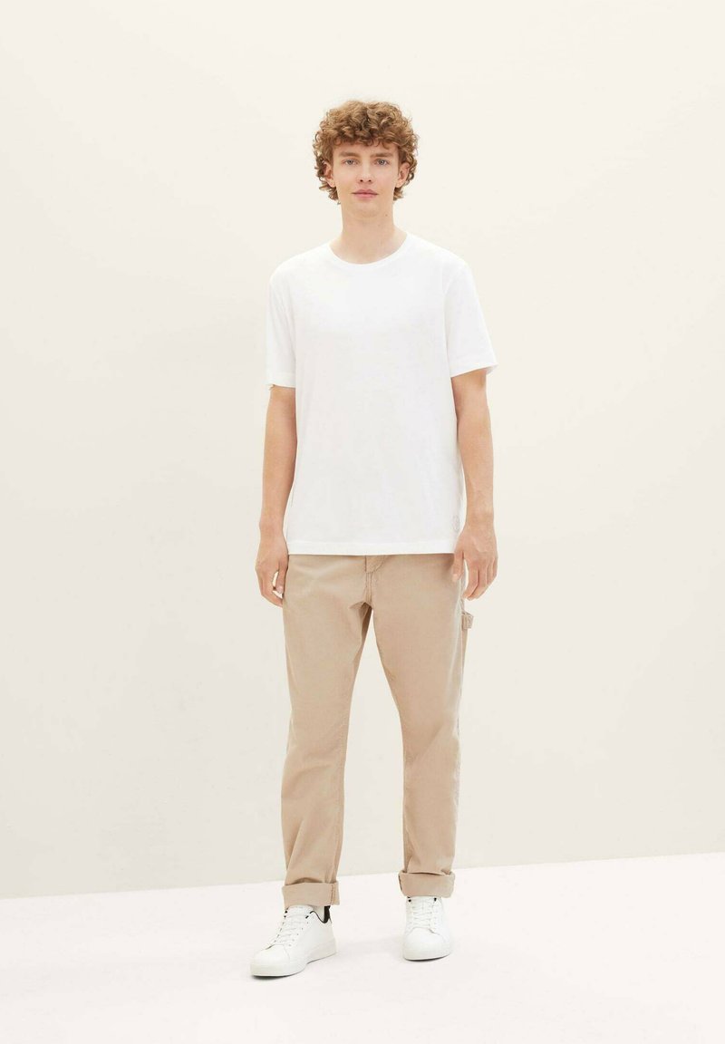 White short-sleeve t-shirt paired with beige chinos and white sneakers. Simple design with a relaxed fit, minimal texture, and no patterns.