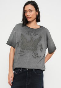 Γκρι φαρδιά μπλούζα από βαμβάκι με υφή, σκούρο γραφικό τύπωμα ενός φοίνικα και το κείμενο "DIESEL 1978" στο μπροστινό μέρος. Κοντά μανίκια.