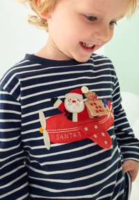 Marineblå og hvide stribede sweater med et festligt rødt flydesign, der forestiller julemanden og en gave. Inklusive tekstureret broderi og detaljer.