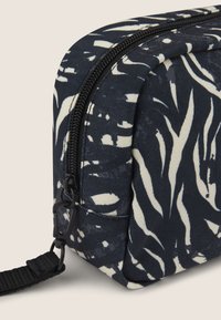 Borsa per cosmetici con zip realizzata in tessuto blu navy con motivi astratti di foglie bianche. Presenta una base piatta e una tracolla removibile. Superficie testurizzata.