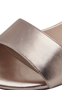 Metallisk roséguldfärgad slide-sandal med bred korsande rem, slät textur, öppen tådesign och lätt böjd form.