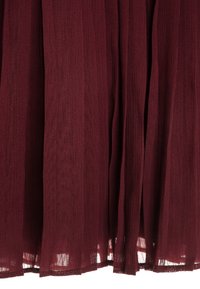 Bordowy przezroczysty materiał z delikatną pionową fakturą i miękkimi fałdami, częściowo prześwitujący na dolnych krawędziach.