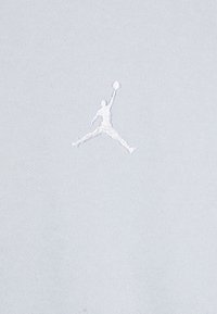Világoskék anyag, fehér, hímzett Jumpman logóval. A textúra sima és a design minimalista.