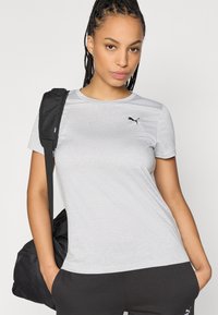 Tricou sport gri din material ușor, cu decolteu rotund și un mic logo negru pe pieptul stâng. Croială confortabilă.