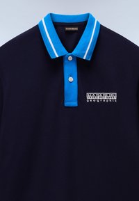 Marineblå polo skjorte med blå krage med hvite striper, to knapper og en hvit brodert "Napapijri geographic"-logo.