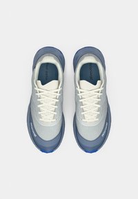 Baskets bleu clair et grises avec un dessus texturé, une semelle épaisse et des lacets blancs. Présente un accent bleu à l'arrière et un logo sur le côté.