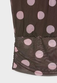 Tissu noir transparent à grands pois roses, avec des détails froncés rassemblés sur la partie inférieure.