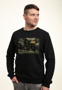 Černá mikina s grafickým potiskem bicyklu se žlutým košíkem, obklopená textem ve stylu graffiti a abstraktními vzory.