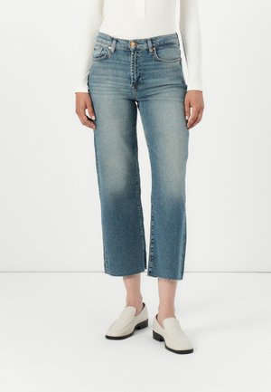 Blauwe denim cropped jeans met een vervaagde afwerking, rafelige zoom, vijfzakontwerp en een aangesloten taille, gedragen met witte instappers.