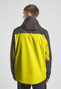 Wasserdichte Jacke mit einem großen, einfarbigen limegrünen Bereich auf dem Rücken und dunkelgrauen Akzenten, mit Kapuze und entspanntem Schnitt.