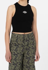 Svart kortärmad topp med rund halsringning, med en liten vit logotyp på bröstet. Matchad med byxor i grön kamouflagemönster.