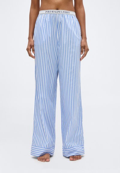 Άτομο φορούν χαλαρό, ανοιχτό μπλε και άσπρο πυρηνικό ριγωτό παντελόνι πιτζάμας με ζώνη μέσης "Polo Ralph Lauren", στέκεται ξυπόλυτο σε λευκό φόντο.