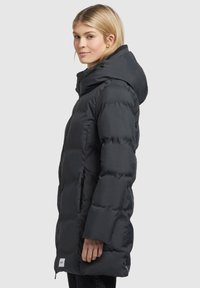 Manteau en duvet noir, avec une capuche, texture matelassée et poches latérales. Le design est de longueur genou avec une silhouette légèrement cintrée.