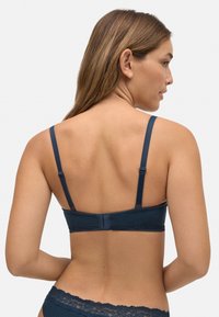 Sujetador de encaje azul marino con tirantes ajustables, tejido texturizado y una banda suave. Presenta un delicado detalle de encaje en los bordes.