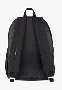 Sac à dos noir avec deux larges bretelles, une poignée de transport en haut et une texture de tissu lisse ; présente une étiquette de logo près du bas.