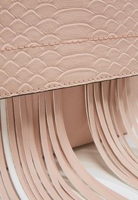 Rosa Handtasche aus Kunstleder mit strukturiertem Schlangenmuster und langen, flachen Fransen am unteren Rand.