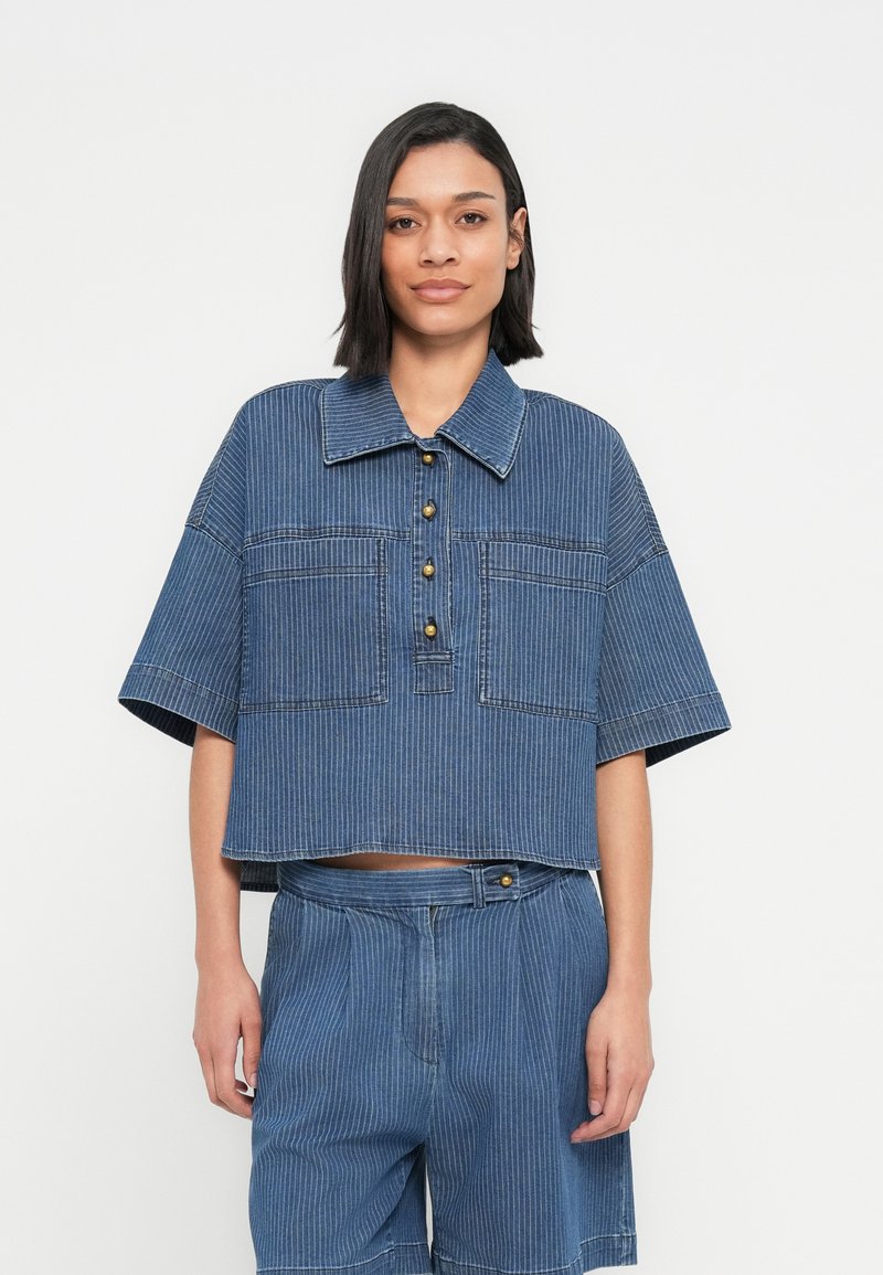 Chemise courte en denim avec col, manches courtes et rayures verticales. Dotée de boutons dorés et de deux poches avant.