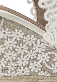 Sandalia espadrille blanca con parte superior de tejido trenzado con detalles de encaje floral, un suave forro interior y una suela de yute natural.