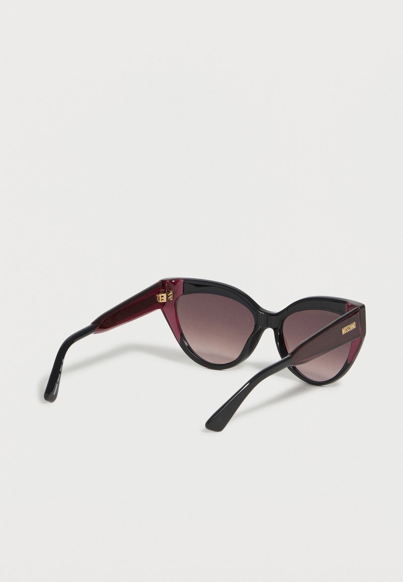 Cat-eye sunglasses with black and dark red frames and gradient gray lenses, Moschino branding on the arm.